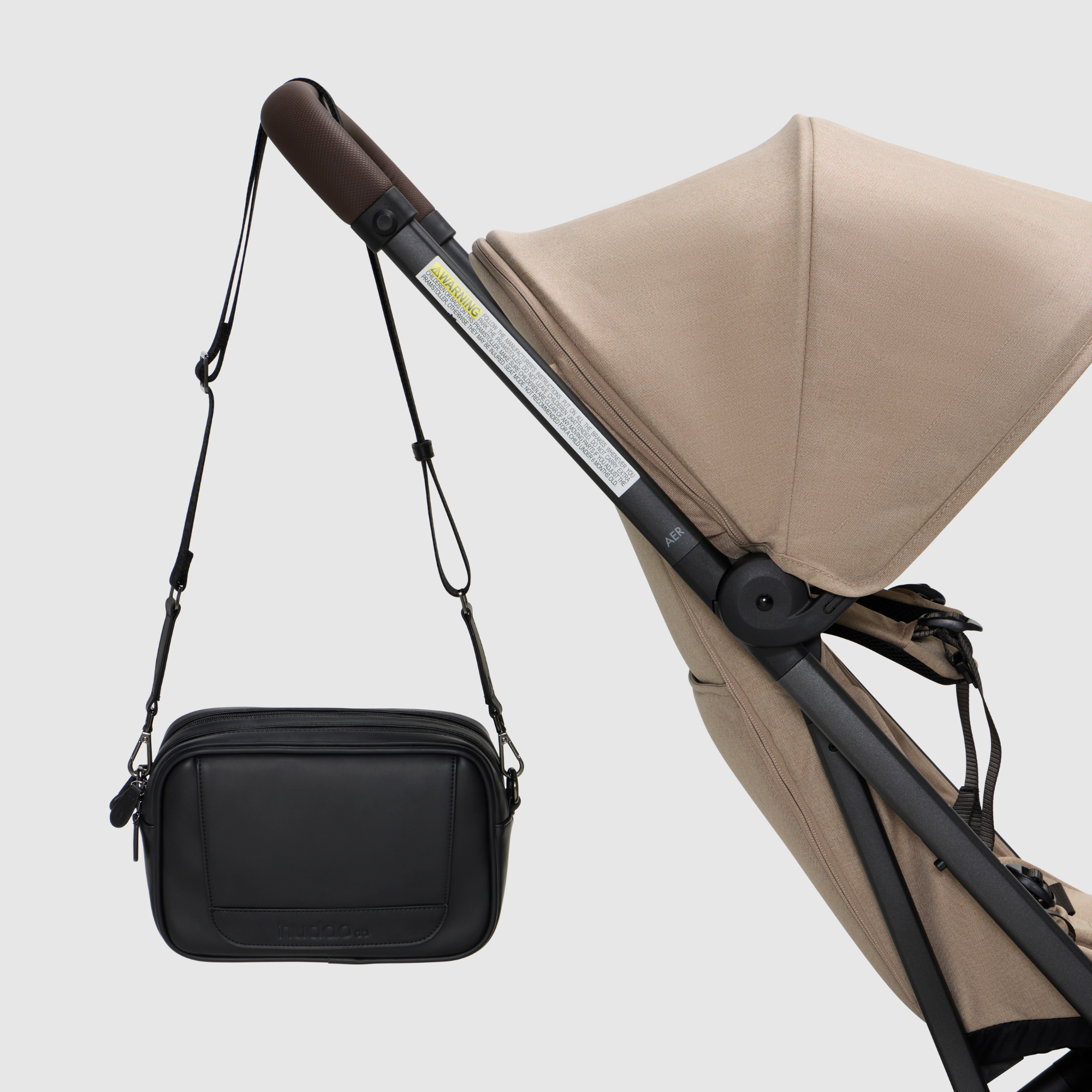 black crossbody baby bag hanging from pram stroller - huddoco mum club crossbody bag