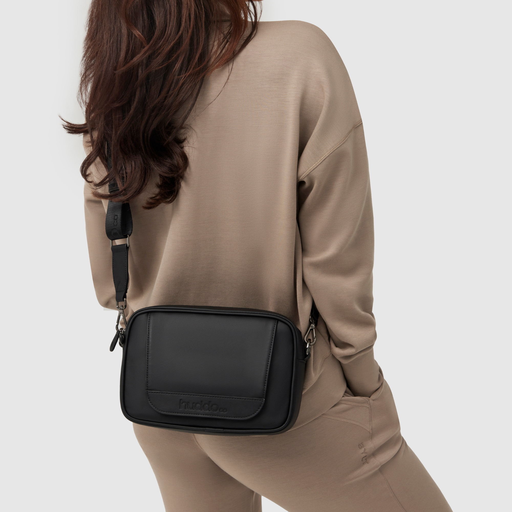 mother wearing huddoco mum club crossbody baby bag in black pineapple leather with wipes dispenser