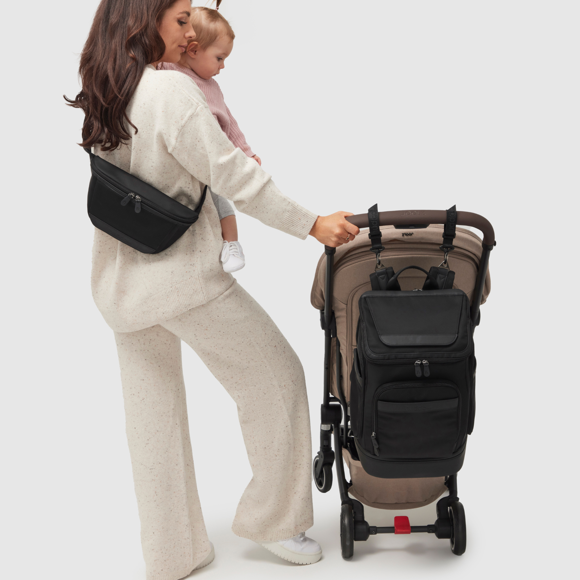 mother and toddler looking at anywhere baby backpack on pram using stroller straps - mother is wearing nappy buddy belt bag