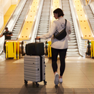 mother with baby at airport with anywhere baby backpack on suitcase using luggage passthrough - mother is wearing nappy buddy belt bag