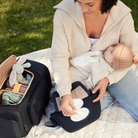 anywhere baby backpack travel bundle nappy bag set - showing mother and baby using bag set in park, using anywhere baby backpack, featuring side access, wipes dispenser with refillable wipes case, nappy buddy belt bag, reusable change mat