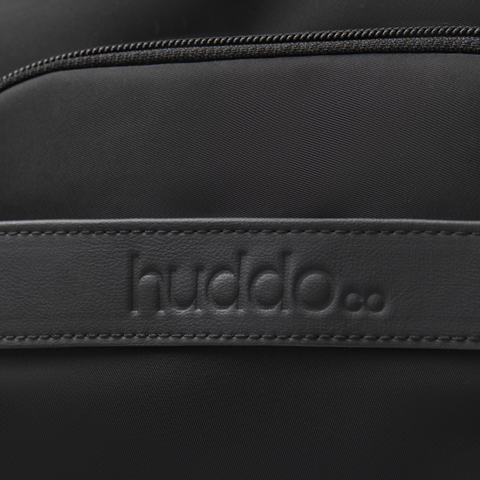 close up of anywhere baby backpack waterproof recycled nylon featuring pineapple leather accent with debossed huddoco logo