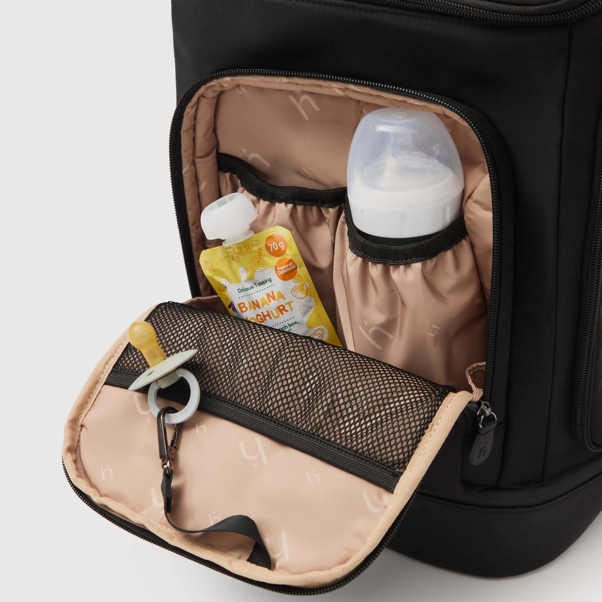 front insulated pocket on huddoco anywhere baby backpack filled with large baby bottle and yoghurt pouch - with dummy on key leash