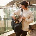 mother using side access on anywhere baby backpack at travel terminal location