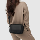 mother wearing huddoco mum club crossbody baby bag in black pineapple leather with wipes dispenser